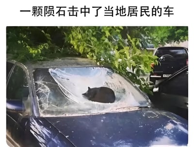 一张幽默搞笑的图片，展示了一辆蓝色汽车的挡风玻璃被完全撞碎，一只黑猫正安静地坐在破碎的玻璃中间。图片上方配有文字“一颗陨石击中了当地居民的车”，形成了有趣的视觉双关——表面上描述陨石撞击事件，实际上暗示这只猫就是“肇事者”，用夸张的方式制造笑点。