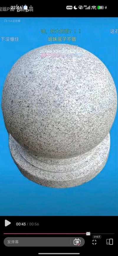 这是一张B站P图类视频的截图，画面主体为一颗带有圆形底座的灰色麻面花岗岩挡车石球，背景为纯净的蓝色。截图保留了B站视频的播放界面元素，顶部有手机状态栏信息，底部显示视频总时长56秒，当前播放到43秒，还有发弹幕、播放控制等功能按钮。画面上方叠加了多条观众发送的弹幕，均是调侃该石球作为P图素材“底子好”，对应“p图前后”的主题，暗示后续会将该普通石球P成效果出众的形象，形成强烈反差趣味。