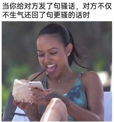 图片上方有文字“当你给对方发了句骚话，对方不仅不生气还回了句更骚的话时”，下方是一位女性的照片。她扎着马尾辫，穿着蓝绿色背心，手里拿着一个带吸管的椰子，同时正在看手机。她脸上带着灿烂的笑容，舌头微微伸出，表情显得非常开心和玩味，完美契合了上方文字所描述的情景。