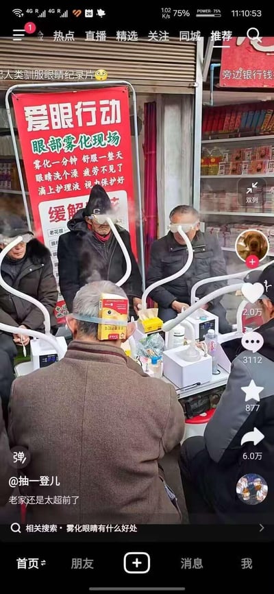 这是一张抖音平台的视频截图，画面呈现了街头的“爱眼行动”眼部雾化护理摊位，几位老年男性正坐着使用雾化设备进行眼部护理，眼罩连接着管道，有雾气从中冒出，其中一位老人的后脑勺还固定着一个眼贴包装盒，显得十分接地气又有喜感。旁边的红色宣传海报写着“爱眼行动 眼部雾化现场”，并标注了“雾化一分钟 舒服一整天”等宣传语，主打缓解眼疲劳、清洁眼睛的功效。视频配文“老家还是太超前了”，顶部还有“人类驯服眼睛纪录片😳”的调侃文字，整体氛围轻松搞笑，展现了接地气的街头养生方式。