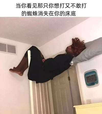 这张梗图展示了一个红头发的人以极其扭曲的姿势躺在床上，头部枕在枕头上，身体却几乎垂直于床面，双腿靠在墙上，呈现出一种非常紧张和警惕的姿态。图片上方配有文字：'当你看见那只你想打又不敢打的蜘蛛消失在你的床底'，幽默地表现了人们发现蜘蛛消失在床底后那种既害怕又警惕的复杂心情。房间内可以看到白色的墙壁、一扇门和一个显示7:03的数字时钟。