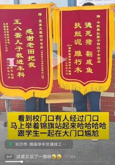 图片展示了两面红色锦旗，上面写着幽默调侃的感谢文字。左边锦旗写着"感谢老田把我王八蛋儿子教进本科"，赠给"完美无瑕的田老师"，日期为二零一四年六月。右边锦旗写着"烫死猪翻咸鱼 扶烂泥雕朽木"，赠给"中职界扛把子田汉子女老师"，由2024届职教高考班学生敬赠，日期为二零二四年六月。锦旗下方有黄色文字说明："看到校门口有人经过门口马上举着锦旗站起来哈哈哈哈跟学生一起在大门口尴尬"。图片底部显示位置信息"长沙市·湖南华中交通技工…"和一条热评"这是又加了一面啊🤣🤣"，获得364个赞。