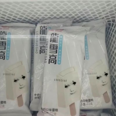 图片展示了多个龙雪高牛奶口味雪糕的包装袋，整齐摆放在一个白色网格篮子中。每个包装袋为白色底色，印有黑色的"龙雪高"品牌名称及英文"LONGXUEGAO"，下方标注"牛奶口味雪糕"和"净含量:72克"。包装上有一个简约的面部插画，特征为两个黑色圆点眼睛和简单的嘴巴线条。