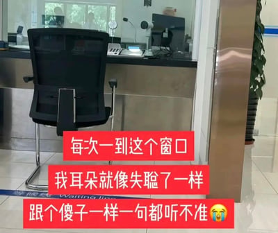 这张图片拍摄于类似银行或政务服务大厅的办事窗口前，前景摆放着一把黑色办公椅，地面有蓝色的“等候线Waiting line”标识，窗口内可见办公设备和工作人员的身影。图片上叠加了三段红色背景的白色文字，并搭配哭泣表情，直白地表达了拍摄者的办事困扰：每次到这个窗口，都听不清工作人员的话语，仿佛失聪一样完全听不准内容，传递出因窗口沟通音效不佳导致办事不畅的无奈与烦躁情绪。