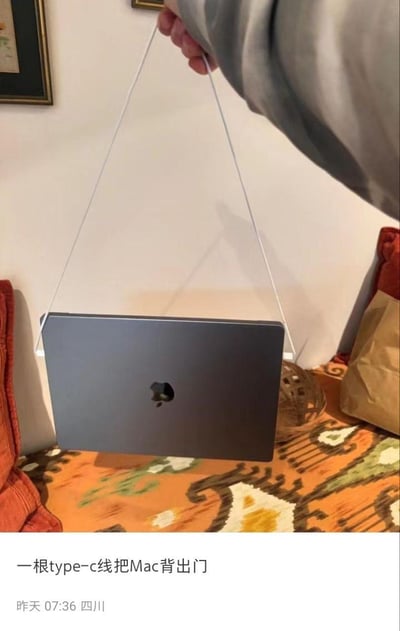 图片中显示一只手正用一根Type-C数据线作为简易提手，将一台银色MacBook笔记本电脑悬空拎起。笔记本下方是带有花纹的橙色布料表面，背景中能看到白色墙壁和部分家具。图片底部配有文字“一根type-c线把Mac背出门”，并显示发布时间“昨天 07:36”和地点“四川”。这种创意但可能存在风险的携带方式形成了有趣的视觉效果，展现了网友的生活小妙招。