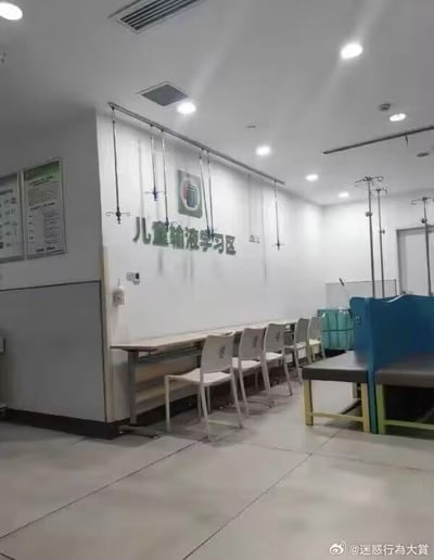 这张图片展示了医院内一个专门的区域，墙面醒目地标注着“儿童输液学习区”的字样。区域内靠墙设置了一排长桌，搭配着多把带靠背的椅子，桌子上方的墙面上安装了多个输液架，方便儿童在输液时使用。同时画面右侧还有可供休息的座椅。这个区域的设置初衷是为了让需要输液治疗的儿童，能够在治疗的同时也有可以学习的空间，兼顾病情治疗和学业，这种设置既带着一丝无奈，又体现出对患儿的贴心考量。