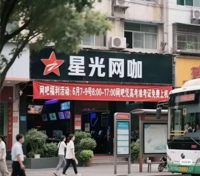 这是一张城市街头实拍图，展示了名为“星光网咖”的网吧门店。门店外悬挂醒目的红色活动横幅，标注了针对高考考生的专属福利：6月7日至9日的8:00-17:00，考生凭高考准考证即可免费上机。画面中还有路过的行人、公交站台与公交车，呈现出日常的城市街景，活动时间恰好覆盖高考考试时段，为考完试的考生提供了放松的去处。