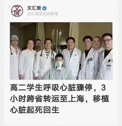 这是一则来自文汇报官方网易号的新闻内容，图片上方是病房场景的合影：一位戴着口罩的高二学生坐在中间，周围环绕着多位身着白大褂的医护人员，背景可见病房的输液设备，整体氛围温馨且充满希望；图片下方配有醒目的新闻文字，讲述了这名高二学生突发呼吸心脏骤停后，经过3小时的跨省转运抵达上海，最终通过心脏移植手术成功获救、起死回生的感人医疗救治案例，传递了医疗技术的力量和生命的奇迹。