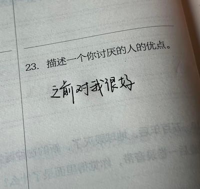 照片展示了一本打开的书的页面，其中第23题题目为“描述一个你讨厌的人的优点。”，下方手写回答为“之前对我很好”。这个简短的回答蕴含了复杂的情感，暗示了即使是现在讨厌的人，过去也曾有过温暖的互动，引发人们对人际关系中矛盾性的思考。