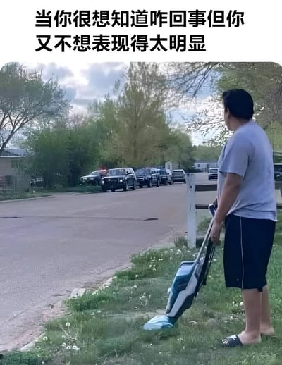 图片上方配有文字“当你很想知道咋回事但你又不想表现得太明显”，下方是一名男子的实拍场景。男子穿着灰色T恤、黑色短裤和拖鞋，手持蓝色割草机站在草坪上，身体却明显扭向街道方向，目光注视着远处停放的多辆警车。他看似在专心割草，实则暗中观察街道上的情况，完美诠释了想了解事情真相又不想显得过于刻意的微妙心态。