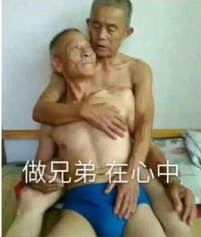 图中呈现了两位赤裸上身的老年男性，一位坐在另一位的腿上，后方的男性从侧面环抱住前方的男性，姿态十分亲密。画面下方配有文字「做兄弟 在心中」，用反差感极强的画面来调侃兄弟情谊，走搞笑无厘头的风格，通过夸张的肢体互动来诠释“兄弟情在心中”的说法，没有双关、谐音梗等内容。