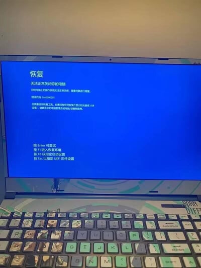 这是一张笔记本电脑的屏幕截图，显示Windows系统的蓝屏恢复界面，提示「无法正常关闭你的电脑」，错误代码为0xc0000001，说明操作系统无法正常关闭需要修复，并提示若无安装介质需联系管理员或设备制造商。界面下方给出了多个操作选项：按Enter可重试、按F1进入恢复环境、按F8指定启动设置、按Esc指定UEFI固件设置。截图下方可见带有定制图案键帽的笔记本键盘，整体场景为电脑系统出现故障，处于待修复状态。