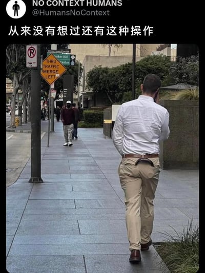 这是一张城市街道人行道的实拍静态图，画面前景是一位背对着镜头的男士，他穿着白衬衫和卡其裤，裤子后腰位置有着类似镂空的奇特设计，搭配皮带形成了极具迷惑性的视觉效果，该男士正手持手机打电话；背景中可以看到其他行人在人行道上行走，街道旁设有禁止停车标识、“THRU TRAFFIC MERGE LEFT”的道路提示牌，以及指向Downtown Center、Bunker Hill Center的路牌，整体是日常的城市街景。图片顶部有社交媒体账号“NO CONTEXT HUMANS”的标识，下方配有中文文字“从来没有想过还有这种操作”，突出了这个奇特裤子穿法的意外感与迷惑性，成为画面的核心笑点。