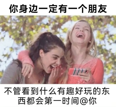 图片上方有文字'你身边一定有一个朋友'，中间是两位女性的合照：黑发女性侧身笑着用手捂嘴，金发女性仰头大笑并手持手机，背景为绿叶树木。下方文字为'不管看到什么有趣好玩的东西都会第一时间@你'，整体表达朋友间乐于分享有趣事物的亲密关系。