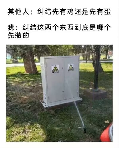 该图为图文混排的搞笑梗图，顶部配文将经典哲学问题“先有鸡还是先有蛋”与现实场景做对比：其他人纠结的是广为人知的经典先后矛盾问题，而“我”则纠结配图里的两个设施哪一个先被安装。配图是户外草坪场景，一个带有高压电警示标识的灰色配电箱立在草坪上，旁边的地埋式喷灌头正对着配电箱持续喷水，从常理来看，如果先安装喷灌就不会将喷水方向对准带电的配电箱，如果先安装配电箱也不会在紧邻位置设置对着它喷水的喷灌，形成了和“先有鸡先有蛋”类似的逻辑矛盾，充满搞笑调侃的效果。
