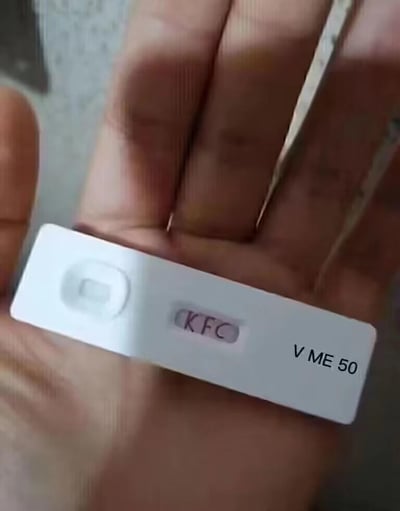 这是一张经过P图改编的恶搞网络梗图，画面中一只真人的手拿着一个样式类似检测试剂（如验孕棒）的白色试纸，试纸的检测结果区域被修改为显示“KFC”字样，右下角还添加了“V ME 50”的文字。这是套用了肯德基“疯狂星期四”的经典玩梗模板，“V ME 50”是“微信转我50”的缩写，结合KFC的标识，整活式地模仿检测结果的形式来引出“疯狂星期四请我吃肯德基，转我50”的玩梗内容，整体风格搞笑戏谑，是网络上常见的整活创作。

梗说明：肯德基疯狂星期四是肯德基的固定促销活动，衍生出大量网络段子，通常以离奇故事开篇，结尾落脚于“今天是肯德基疯狂星期四，v我50”，这张图用检测试纸的形式重构了这个梗的表达，将“检测出KFC”作为由头，自然带出转钱的玩梗诉求。