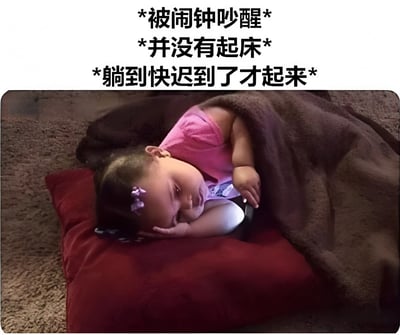 图片上方有三行中文文字："*被闹钟吵醒*"、"*并没有起床*"和"*躺到快迟到了才起来*"。图片下方是一个婴儿躺在红色枕头上，身上盖着棕色毯子，头上戴着紫色发饰，穿着粉色上衣，呈现出困倦休息的状态。这张图通过可爱婴儿的形象和文字内容，幽默地表现了很多人被闹钟吵醒后仍然赖床不起，直到快要迟到才起床的常见生活场景。