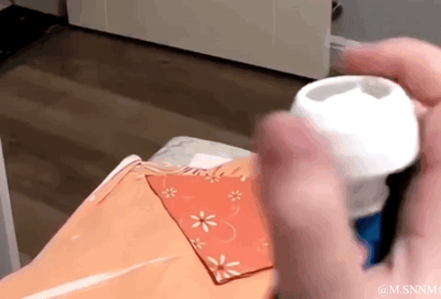 这是一个动态图（GIF），画面中一只真人的手在带有白色瓶口的容器旁反复做出捏握动作，通过手部移动的位置和容器的配合，制造出仿佛手正在捏起瓶口白色部分的视觉错位效果，让观看者产生瓶口白色部分是可捏动的软质物体的错觉，实际只是手部动作与容器位置巧合形成的视觉假象，整体画面充满趣味和新奇感。