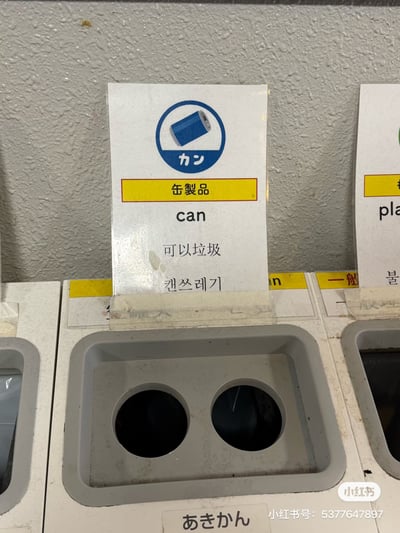 这是一张拍摄于日本的分类垃圾桶实拍图，垃圾桶上方的标识牌用于指引易拉罐类垃圾投放，标识上依次标注了日文“カン”“缶製品”、英文“can”，但中文翻译却错误地写成了“可以垃圾”，同时还有韩文“캔쓰레기”标注。这个完全不符合中文表达逻辑的错误翻译，显得生硬又滑稽，属于生活中出现的翻译乌龙，自带搞笑效果。