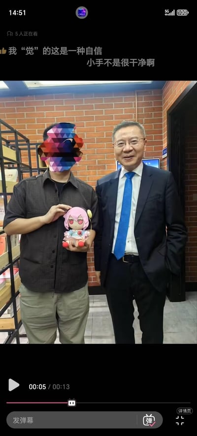 这是B站直播的画面截图，画面右侧是学者张维为，身着深色西装搭配蓝色领带，面带微笑；左侧的粉丝脸部被马赛克处理，手持一个粉色头发、红眼睛的Q版动漫玩偶，与张维为并肩合影。画面上方的弹幕包含“我‘觉’的这是一种自信”“小手不是很干净啊”，其中“觉”是谐音梗，玩了和张维为相关言论风格的文字游戏。