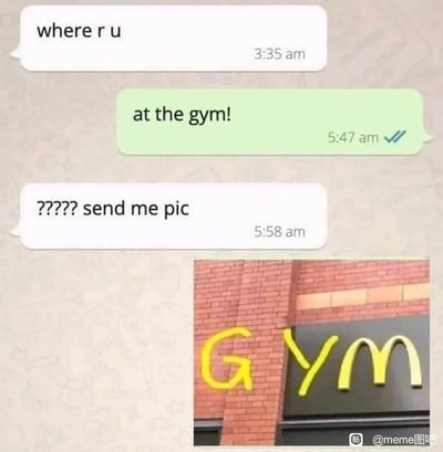 这是一张结合聊天记录截图与P图创作的搞笑meme梗图。凌晨3:35，一名用户向对方发送消息询问“你在哪”，对方在5:47回复称自己“在健身房！”，询问者对此表示质疑，连发问号并要求对方发送现场照片；随后对方发送了一张经过修改的麦当劳门店照片：在麦当劳标志性的“M”标志左侧，用黄色涂鸦添加了字母“G”和“Y”，拼凑出英文“GYM（健身房）”的字样，以此玩视觉文字游戏，用糊弄的方式制造出“把麦当劳伪装成健身房”的搞笑效果，调侃了深夜不去健身反而吃麦当劳的行为。