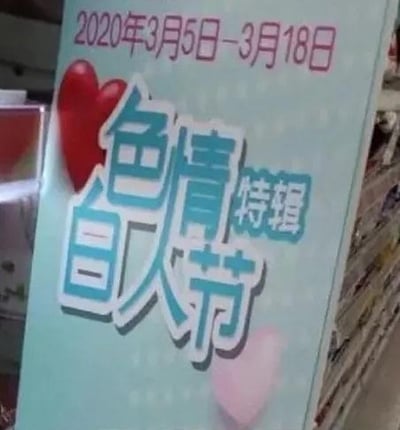 一张拍摄的宣传牌照片，背景为浅蓝色带有白色圆点图案。上方显示日期"2020年3月5日-3月18日"，中间有红色和粉色的心形装饰，主要文字内容为"色情白人节特辑"，其中"色情"二字使用白色立体字体，"白人节特辑"使用蓝色字体。宣传牌似乎放置在商店货架之间的环境中。