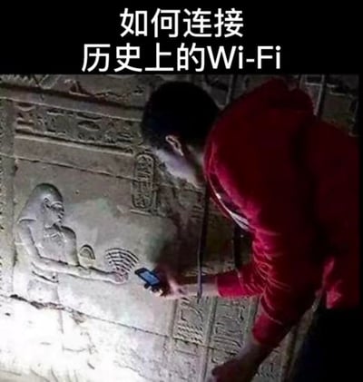 这是一张错位拍摄的搞笑梗图，画面里一位穿红色衣服的游客在埃及神庙的浮雕前，将手机对准浮雕中神祇伸出的、形似WiFi信号图案的手掌，配合顶部的文字“如何连接历史上的Wi-Fi”，制造出古代神祇在提供WiFi信号、游客正在扫码连接的趣味错觉。

笑点解析：这个梗的趣味点来自视觉错位，把古埃及浮雕的手势和现代WiFi信号图标巧妙关联，形成古代文明与现代科技穿越时空的幽默反差。