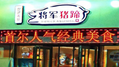 这是一张线下韩式餐饮店的门头实拍图，店铺主招牌为带有猪蹄轮廓造型的「将军猪蹄」字样，搭配韩文“한국에서 온 족발”和英文“GENERAL”，强调韩式血统；下方的电子滚动屏显示「首尔人气经典美食」，突出店铺主打韩式猪蹄料理，整体营造出正宗韩式风味的餐饮氛围。