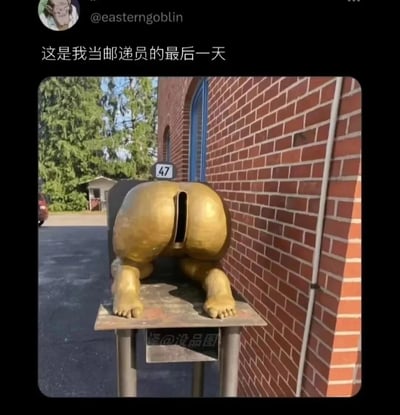社交媒体用户@easterngoblin发布的内容，配文“这是我当邮递员的最后一天”。图片主体为一尊金色臀部造型的雕像，雕像呈俯身姿势，臀部中央有一孔洞，放置在金属基座上。背景可见红砖墙、绿色树木、小型白色建筑及标有“47”的门牌号。底部有水印“怪@没品图”。整体通过邮递员最后一天遇到的奇葩雕像制造幽默效果，展现日常工作中的意外趣事。