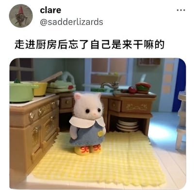 图片展示了一个可爱的白色小猫玩偶站在玩具厨房里，表情呆萌，似乎在思考。玩偶穿着蓝色连衣裙，戴着白色领子，脚上是黄色鞋子。厨房场景布置精致，有灶台、水槽、锅碗瓢盆和食物模型。图片上方有文字'走进厨房后忘了自己是来干嘛的'，幽默地表达了人们常有的健忘时刻，特别是走进房间却忘记原本目的的经历。