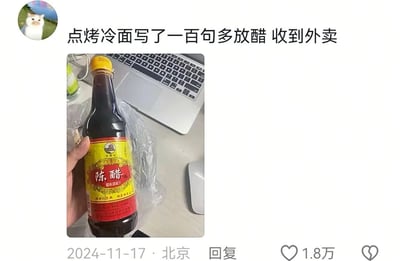社交媒体用户分享点外卖趣事：点烤冷面时在备注里写了一百句“多放醋”，结果收到外卖时发现商家直接附赠了一整瓶陈醋。图片中可见一只手握着黄色瓶盖的陈醋瓶，背景是办公桌和笔记本电脑，配文幽默吐槽这一“硬核”满足需求的方式。