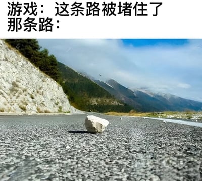 图片上方配有文字“游戏：这条路被堵住了 那条路：”，下方是一张实拍的山路照片。照片中，宽阔的沥青路面中央只有一块小小的石头，周围是连绵的山脉和蓝天白云，整体场景开阔。该梗图通过对比游戏中常出现的“道路被堵”设定与现实中微不足道的障碍物，幽默调侃游戏设计中常见的夸张阻塞情节。