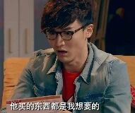 图片中是一位戴着眼镜、留着短发的男性，身穿牛仔夹克，坐在沙发上，面部表情呈现出惊讶的状态。图片底部有一行字幕文本：“他哭的东西就是我想要的”。整体场景像是电视剧或电影中的某个片段截图，人物的表情与字幕内容形成呼应，似乎在表达对他人所拥有事物的渴望。