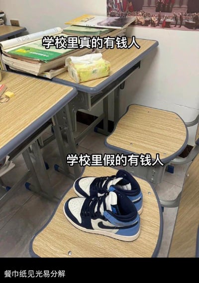 这是一张校园场景的反讽梗图，通过上下两个场景的对比调侃学校里的消费反差：上方堆满书本的课桌上放着一包抽纸，配文“学校里真的有钱人”；下方椅子上摆着一双AJ运动鞋，配文“学校里假的有钱人”，底部还有“餐巾纸见光易分解”的吐槽文字。用反讽的方式，调侃那些省吃俭用购买名牌鞋来彰显“有钱”的学生，和日常使用抽纸、低调的“隐形富豪”形成鲜明反差，充满搞笑的调侃意味。