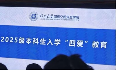 图片展示的是郑州大学网络空间安全学院2025级本科生入学'四爱'教育的现场投影画面。屏幕上方左侧为郑州大学校徽，右侧配有学院中英文名称“郑州大学网络空间安全学院 SCHOOL OF CYBER SCIENCE AND ENGINEERING, ZZU”，中间蓝色背景区域以白色加粗字体显示活动主题“2025级本科生入学‘四爱’教育”，画面底部可见部分参会人员的头部轮廓，推测为新生入学教育讲座或动员大会的现场场景。