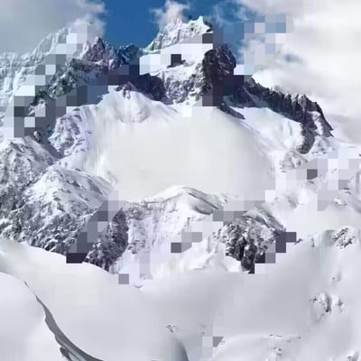 这是一张雪山风景图，展示了被白雪覆盖的连绵山脉，山峰高耸入云，部分山体呈现出岩石的灰色纹理。天空呈现出蓝色，带有少量白云。图片的显著特点是在山脉的不同位置分布着明显的像素化处理效果，形成了方形的色块区域，与周围清晰的雪景形成对比。