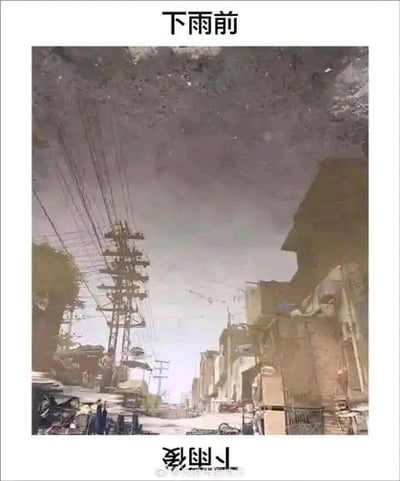 图片展示了一幅倒置的街景画面，上方有文字“下雨前”。画面中可见高耸的电线杆、交错的电线、两侧的低矮建筑物以及街道上的行人，天空呈现阴沉的灰色调，整体氛围压抑，符合下雨前的天气特征。当将图片翻转正立时，原本倒置的街景会呈现出正常视角下的“下雨前”场景，利用简单的翻转手法营造出“颠倒看到另一个世界”的视觉趣味效果。