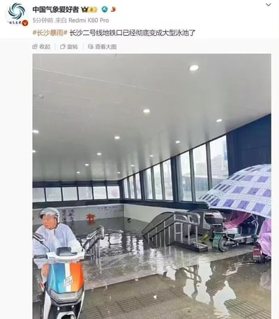 这是一张微博截图，由认证账号“中国气象爱好者”发布，内容展现了长沙遭遇暴雨后的城市内涝场景：当地二号线的一处地铁口被严重淹没，积水几乎没过入口台阶，如同小型泳池。画面中一位身着雨衣的市民正骑着电动车在积水中行进，一旁还停放着被雨具覆盖的电动车，整体场景直观呈现出极端暴雨天气对城市交通设施的破坏，以及给市民出行带来的极大阻碍。
