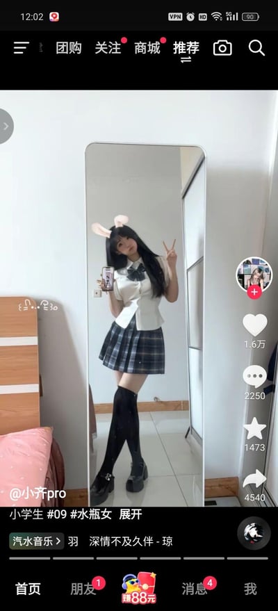 这是一张抖音平台的视频截图，画面中一位女生在室内对着全身镜自拍，她穿着白色收腰短袖衬衫搭配格纹百褶JK裙，搭配过膝黑袜与厚底鞋，头上添加了兔子耳朵特效，一只手比出剪刀手，风格软萌可爱，是分享个人穿搭的日常内容。图中无谐音梗、双关或暗示类内容。