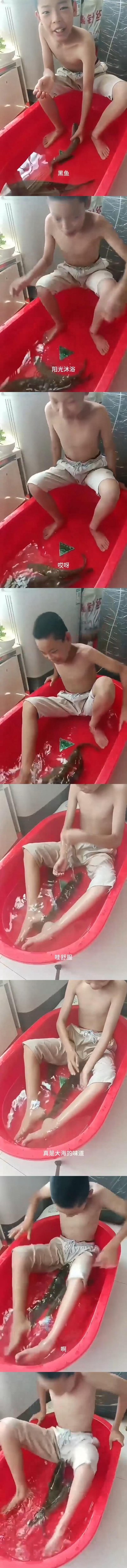 这是一组竖屏连环视频截图，记录了一位光膀子的小男孩在红色水盆中与黑鱼互动的搞笑过程：起初男孩坐在盆边，画面标注“黑鱼”，当他伸手触碰黑鱼时，鱼突然游动，男孩被吓得手忙脚乱，直接坐到了水盆里，后续在水中还被鱼逗得一惊一乍，配合“阳光沐浴”“哎呀”“哇”“哇舒服”“真是大海的味道”“啊”这些趣味加注文字，全程充满反差感，是充满欢乐的日常逗趣生活记录。