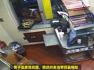 这是一张监控视角的视频截图，画面呈现的是麦当劳的操作间场景，一名男子身处柜台下方的空间中，双手端着一个盛放物品的托盘，似乎正准备递出托盘里的东西。图片底部被添加了带有反讽意味的字幕“男子虽家境贫困，但仍对麦当劳倾囊相助”，通过字面意思与画面场景的反差制造搞笑效果，调侃该男子的行为像是在占用麦当劳的资源，与“倾囊相助”的字面意思完全相反，形成幽默的讽刺感。
