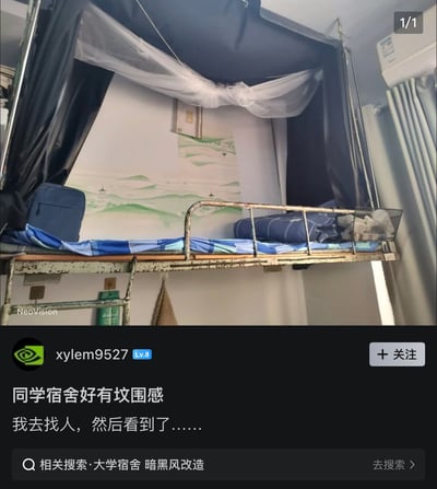 这是一张社交媒体图文截图，上半部分展示了大学宿舍的上层床位：床位外侧安装了黑色遮光床帘，床帘顶部悬挂着白色蚊帐，床头墙面贴有淡绿色调的山水主题装饰画，床铺铺有蓝白格纹的床单，封闭的围合结构搭配背景的山水装饰，视觉上类似坟冢的造型。下半部分是发帖用户的发言内容，用户xylem9527配文调侃该床位“同学宿舍好有坟围感，我去找人，然后看到了……”，底部还显示相关搜索提示“大学宿舍 暗黑风改造”，整体内容玩“氛围感”的谐音梗，充满搞笑趣味。
