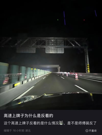 夜间高速公路场景，从车内视角拍摄，道路空旷，右侧有多个红白相间的交通锥。远处可见隧道入口灯光，上方有大型交通标志牌结构，但标志牌内容因拍摄角度或实际安装问题呈现反向状态。图片下方配有文字提问：“高速上牌子为什么是反着的 这个高速上牌子反着的是什么情况😿，是不是师傅装反了”，表达了对交通标志安装方向的疑惑。