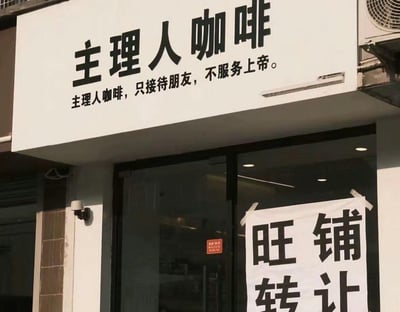 一家名为‘主理人咖啡’的店铺门头照片，招牌上用黑色大字写着‘主理人咖啡’，下方配有个性标语‘主理人咖啡，只接待朋友，不服务上帝’，展现出店铺独特的经营理念。然而玻璃门上却贴着一张白色告示，上面写着‘旺铺转让’四个黑色大字，与招牌上的自信宣言形成鲜明反差，充满了黑色幽默的喜剧效果。