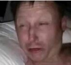 图片中显示一名男性躺在床上，背景为白色床单，他的表情看起来充满悲伤或痛苦，整体氛围较为沉重。