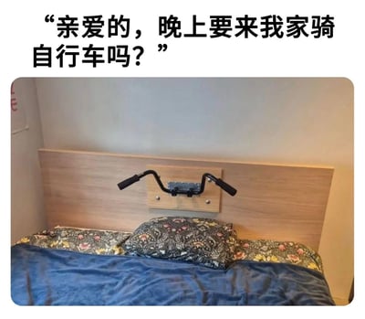 这是一张顶配底文的搞笑梗图，顶部配有文字“亲爱的，晚上要来我家骑自行车吗？”，下方是实拍的卧室场景：床头的木质靠背板上固定安装了一个造型与自行车车把完全一致的黑色扶手，正对着床铺的位置。内容利用语义与场景的结合制造双关效果：表面是邀请对方来家中骑行，实际结合床头特殊的扶手装置，暗示情侣间的床上互动，形成反差幽默感。