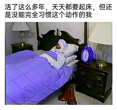 这张梗图上方配有文字：'活了这么多年，天天都要起床，但还是没能完全习惯这个动作的我'，下方是一张卧室场景图。图中展示了一个玩具角色躺在床上，盖着紫色被子，床头有一个蓝色闹钟，床头柜上有台灯，地上放着一双棕色鞋子，床头柜上还有一个写着'PLAY'的字母装饰。图片通过玩具角色赖床的场景，幽默地表达了人们对起床这件日常事情的抗拒和无奈，引发观众共鸣。