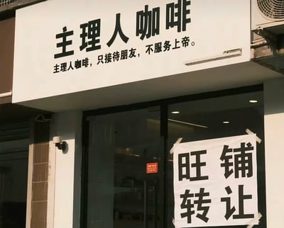 这张图片展示了一家名为“主理人咖啡”的咖啡店，店招标语写着“主理人咖啡，只接待朋友，不服务上帝”，门上却贴着巨大的“旺铺转让”四字公告。这种强烈反差带有幽默和自嘲意味，讽刺了只服务熟人、小圈子优越感的经营方式最终难以为继，成为近年来社交网络热门的创业类现实梗。

图片内蕴含了双关意味：一方面自诩独特品味不做大众生意，另一方面现实却需要把“旺铺”转让，形成反差笑点。