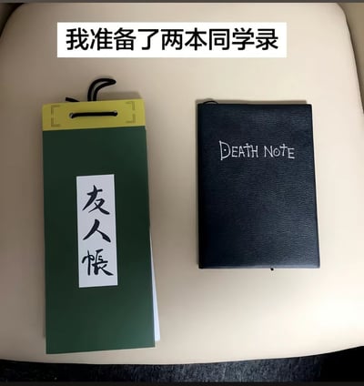 这是一张顶配底文的实拍玩梗图，顶部配有白底黑字的说明文字“我准备了两本同学录”，下方浅色平面上并排摆放着两本模仿知名动漫道具的笔记本：左侧是绿色封皮、黄色装订区域、贴有“友人帐”竖排白色标签的笔记本，原型是动漫《夏目友人帐》中记录妖怪名字、持有该本子就能号令对应妖怪的友人帐；右侧是黑色仿皮封皮、印有白色“DEATH NOTE”字样的笔记本，原型是动漫《死亡笔记》中写下名字就会让对应人物死亡的死亡笔记。创作者借用两部动漫里这两种记录名字就会产生特殊效果的道具设定，调侃毕业季填写同学录的行为，反差感十足，趣味满满。