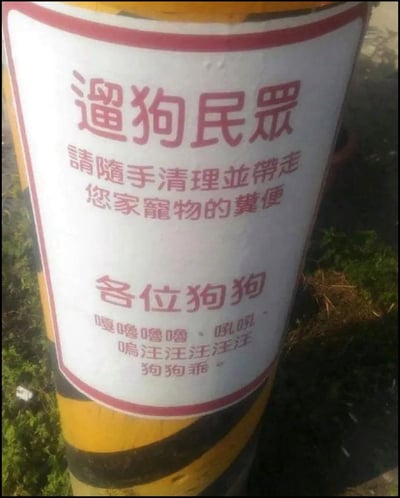 一张拍摄于户外的告示牌照片，展示了一个黄色和黑色条纹底座的圆柱形柱子，上面有一个白色背景红色边框的告示。告示分为两部分：上半部分用正式语言提醒"遛狗民眾 請隨手清理並帶走您家寵物的糞便"，下半部分则用拟人化的方式对狗狗说话，包含模仿狗叫声的拟声词"嘷嘷嘷嘷、吼吼、嗚汪汪汪汪汪"，最后以"狗狗乖"结尾。这种将正式通知与动物语言结合的创意方式，既传达了公共卫生信息，又增添了趣味性。